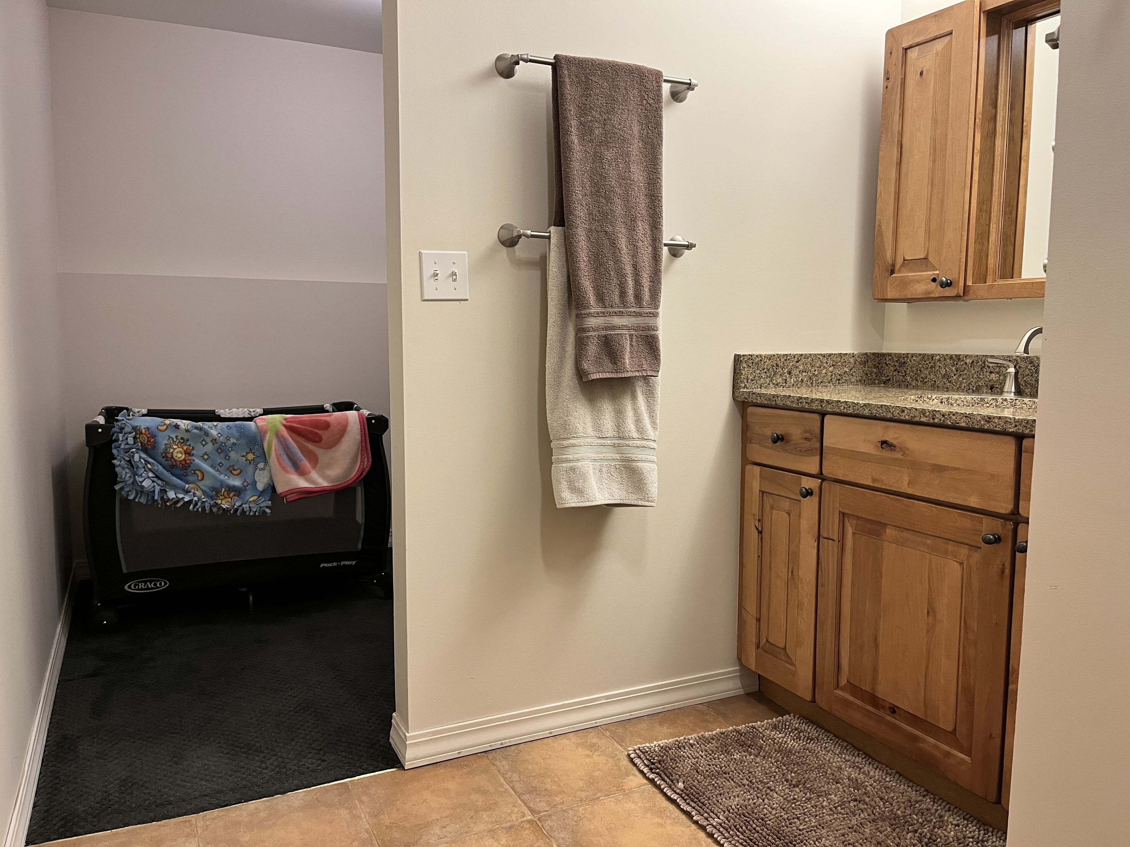 A bathroom with a wooden cabinet, a towel rack, and a tiled floor.