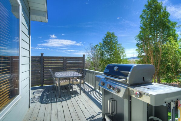 A deck with a grill, a table, and chairs.