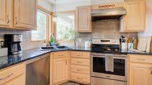 A modern kitchen with light wood cabinets, stainless steel appliances, and a large window providing natural light. - Yellowstone Country Home - Launchpad for a trip of a lifetime!  (Livingston)