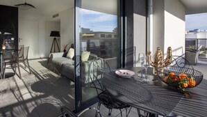 A modern balcony with a glass door, a dining table with chairs, and a decorative bowl of fruit. - Le Grey Pearl by Interhome (Cagnes-sur-Mer)