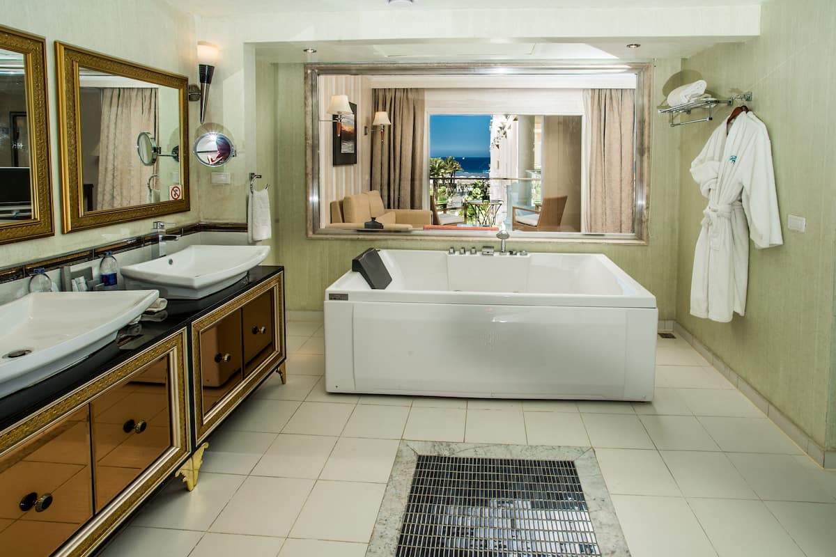 A bathroom with two sinks, a bathtub, and a large mirror.
