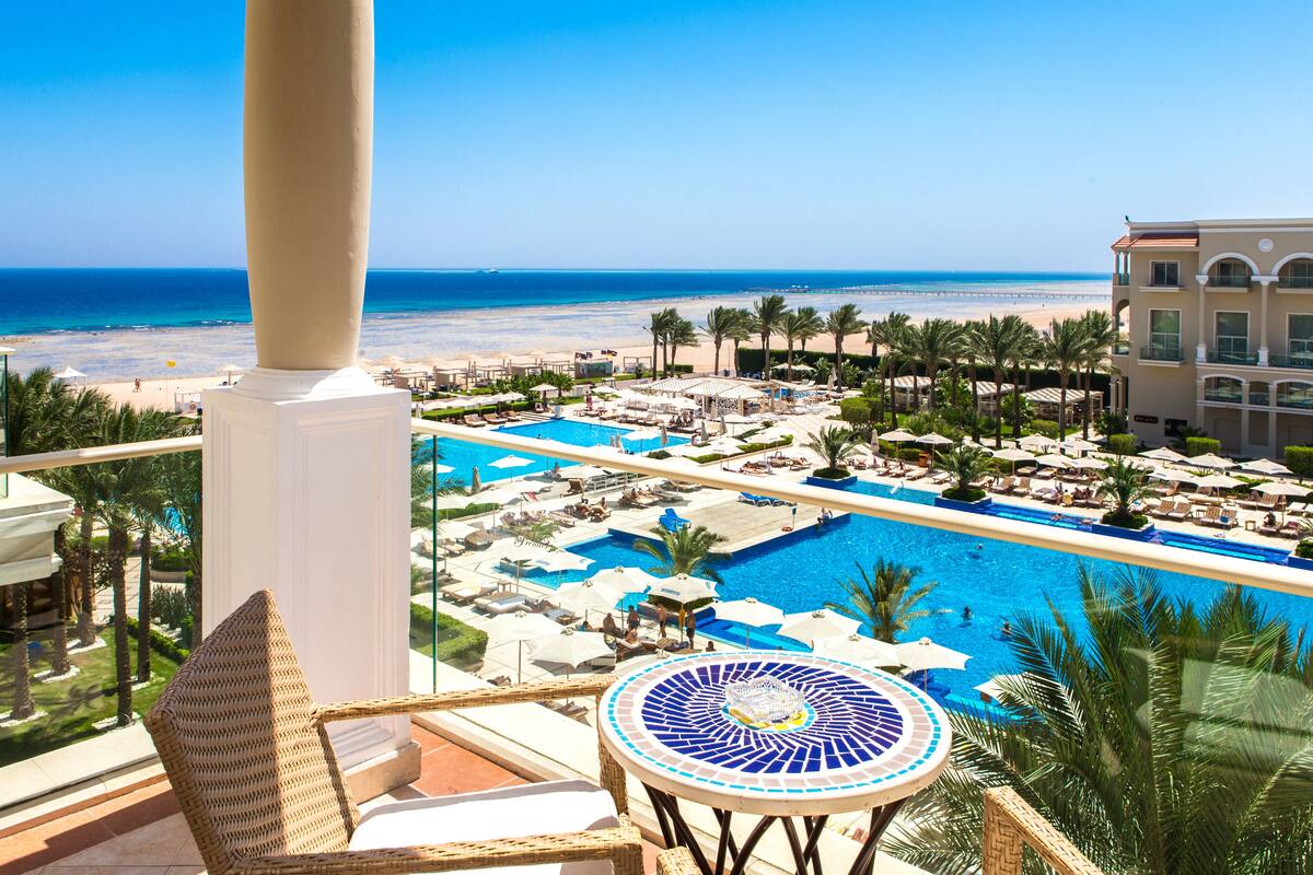 A resort with a large pool, beach view, and multiple lounge areas.
