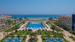 Un complexe hôtelier doté de plusieurs piscines, de palmiers et offrant une vue sur la mer.