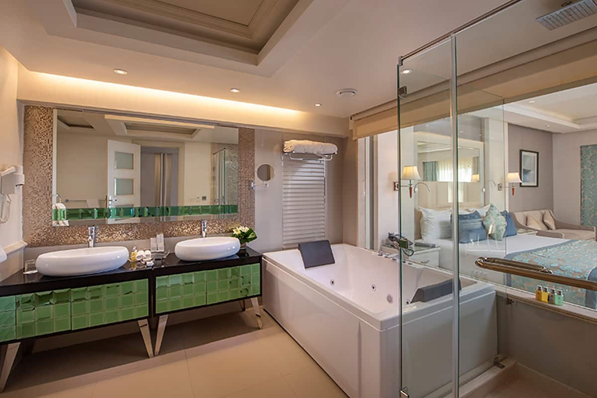 A modern bathroom with dual sinks, a large bathtub, and a glass-enclosed shower.