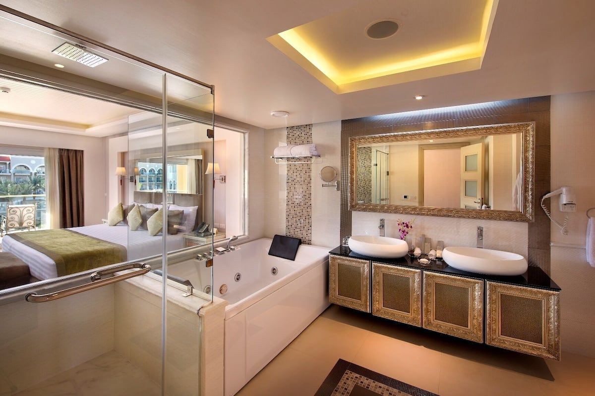 A modern bathroom with a glass-enclosed shower, a large freestanding bathtub, and a vanity with two sinks.