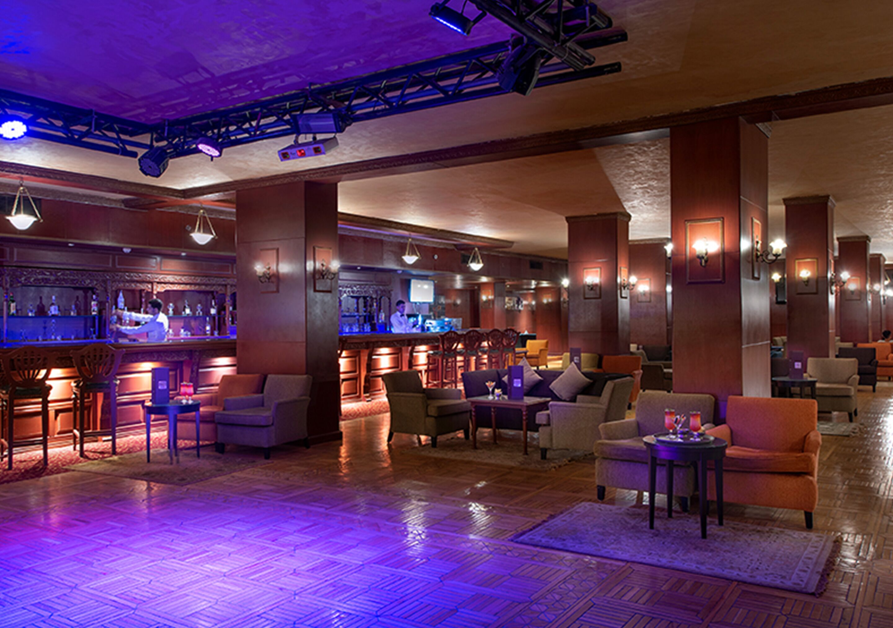 A spacious lobby with a bar area, comfortable seating, and a polished wooden floor.