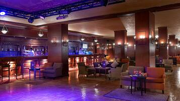 A spacious lobby with a bar area, comfortable seating, and a polished wooden floor.