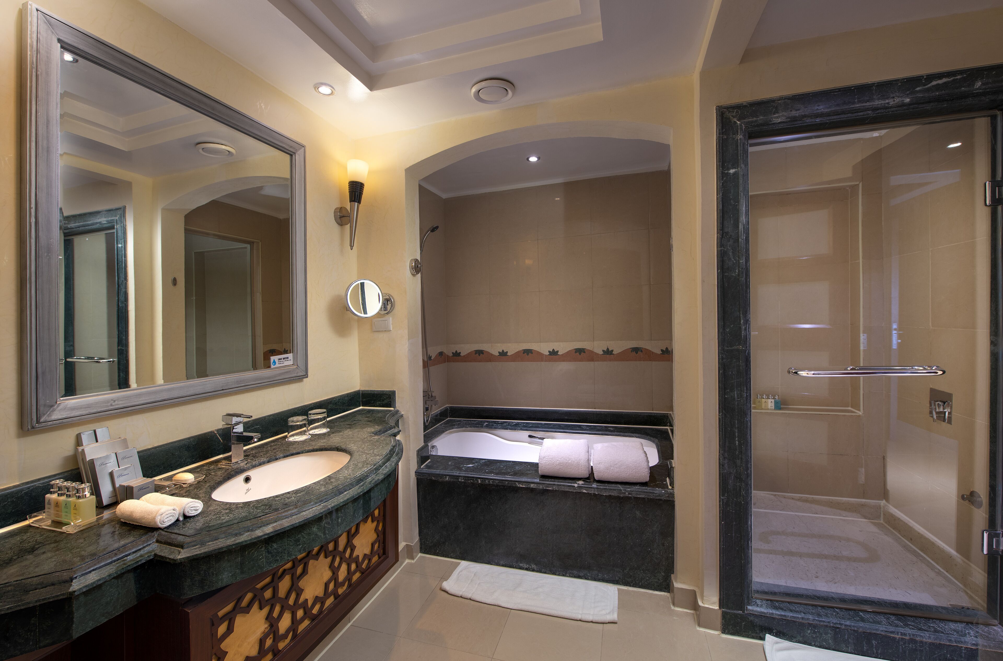 Un bagno con un ampio specchio, due lavandini, una vasca e una doccia.