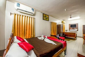 A hotel room with a bed, a desk, a chair, an air conditioner, and a television. - Malar Residencey (Puducherry)