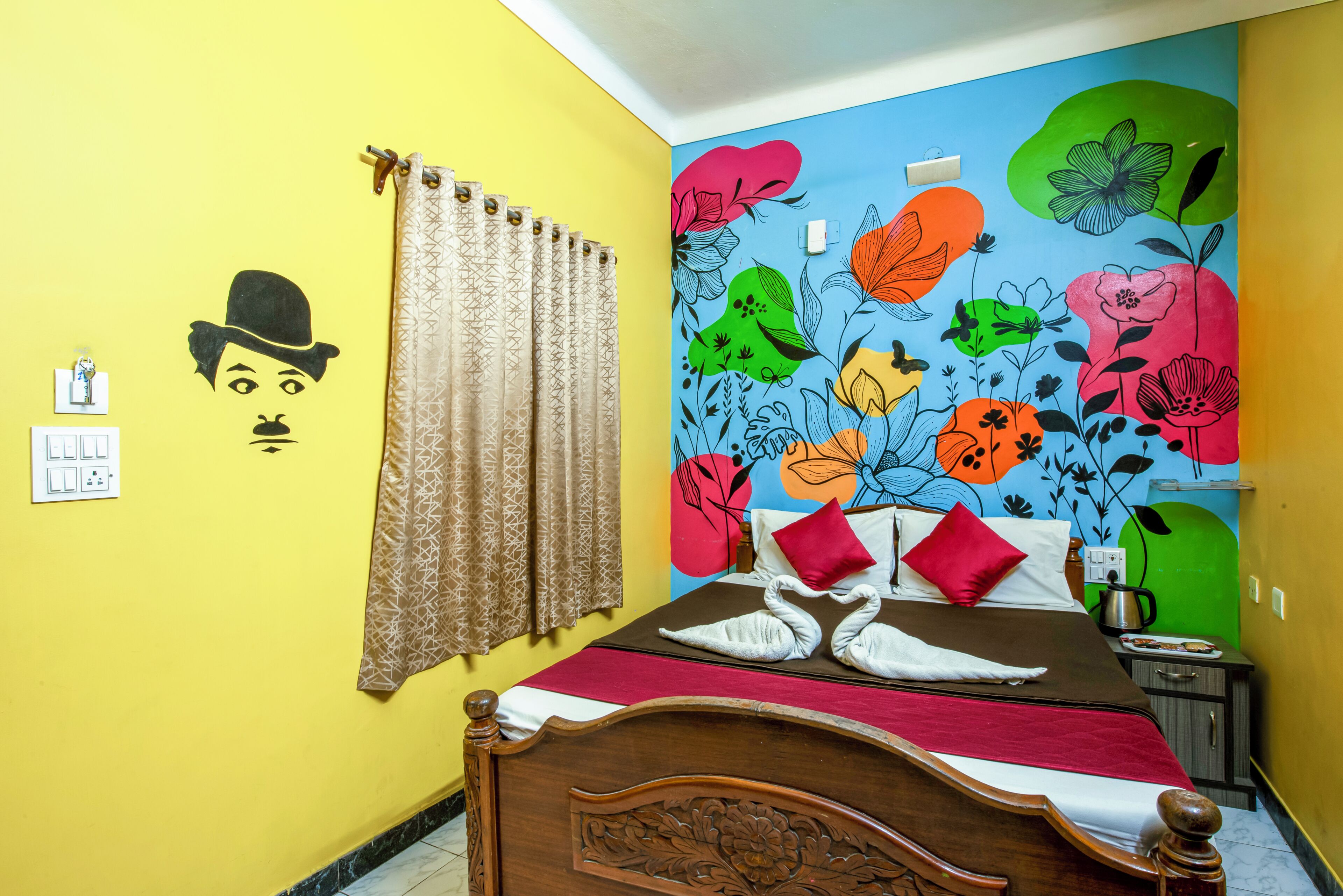 Quarto com cama, cortina, parede com arte floral e interruptor de luz fixado na parede.