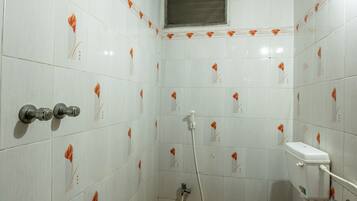 Baño con paredes de azulejos blancos, un inodoro, una ducha y un lavamanos.