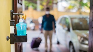 A door with a hand sanitizer dispenser and a suitcase on the floor. - Malar Residencey (Puducherry)