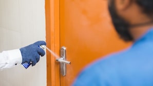 A person using a spray bottle near a door handle. - Malar Residencey (Puducherry)