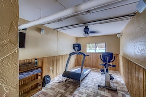 A small gym with a treadmill, stationary bike, and a fan.