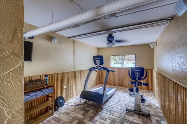 A small gym with a treadmill, stationary bike, and a fan.
