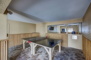 A ping pong table in a room with a tiled floor and a wooden wall.