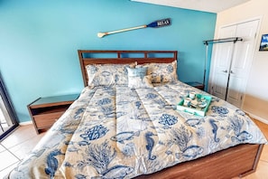 A bedroom with a bed, a nightstand, a wall-mounted paddle, and a door. - Siesta Resort | Private Beach | Gulf Views | Pool (Sarasota)