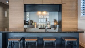Una cocina moderna con una isla central, electrodomésticos de acero inoxidable y taburetes de madera.