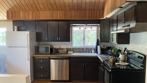 Une cuisine moderne avec des meubles en bois foncé, des appareils électroménagers en acier inoxydable et une fenêtre qui laisse entrer la lumière naturelle.