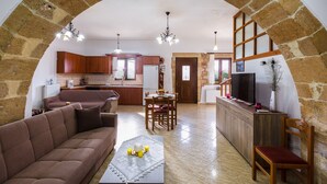 Ein geräumiger Wohnbereich mit einem Steingewölbe, einem Sofa, einem Couchtisch und einem Fernseher auf einer Holzkommode.