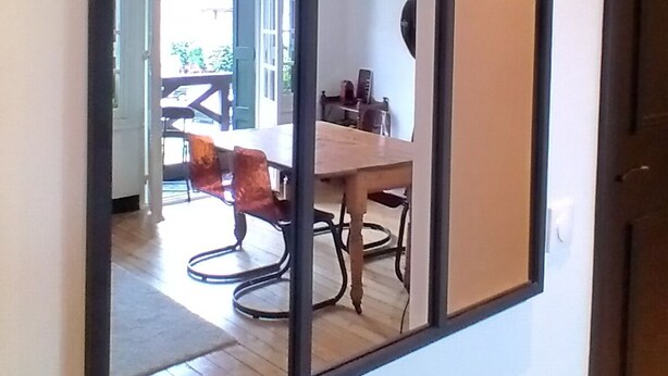 Ein Zimmer mit einem großen Spiegel, der einen Essbereich mit Tisch und Stühlen reflektiert.