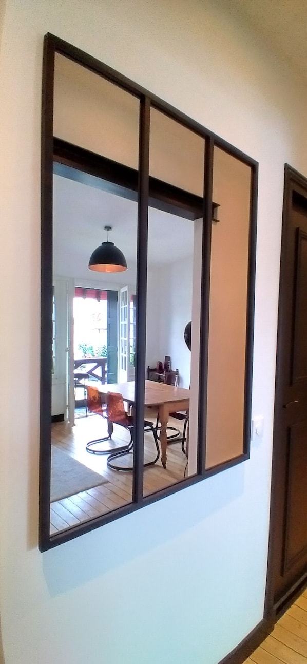 A room with a large mirror reflecting a dining area with a table and chairs.