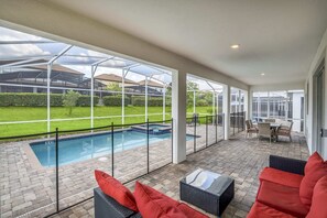 A covered outdoor swimming pool area with a patio, seating, and a view of the backyard. - Luxurious, Grand Home, Themed Bedrooms and Large Pool Area #8cg099 (Davenport)