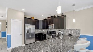 Una cocina moderna con encimeras de granito, electrodomésticos de acero inoxidable y muebles de cocina oscuros.
