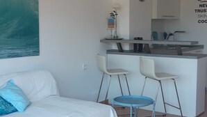 Una habitación moderna con cama, una mesita y una kitchenette.