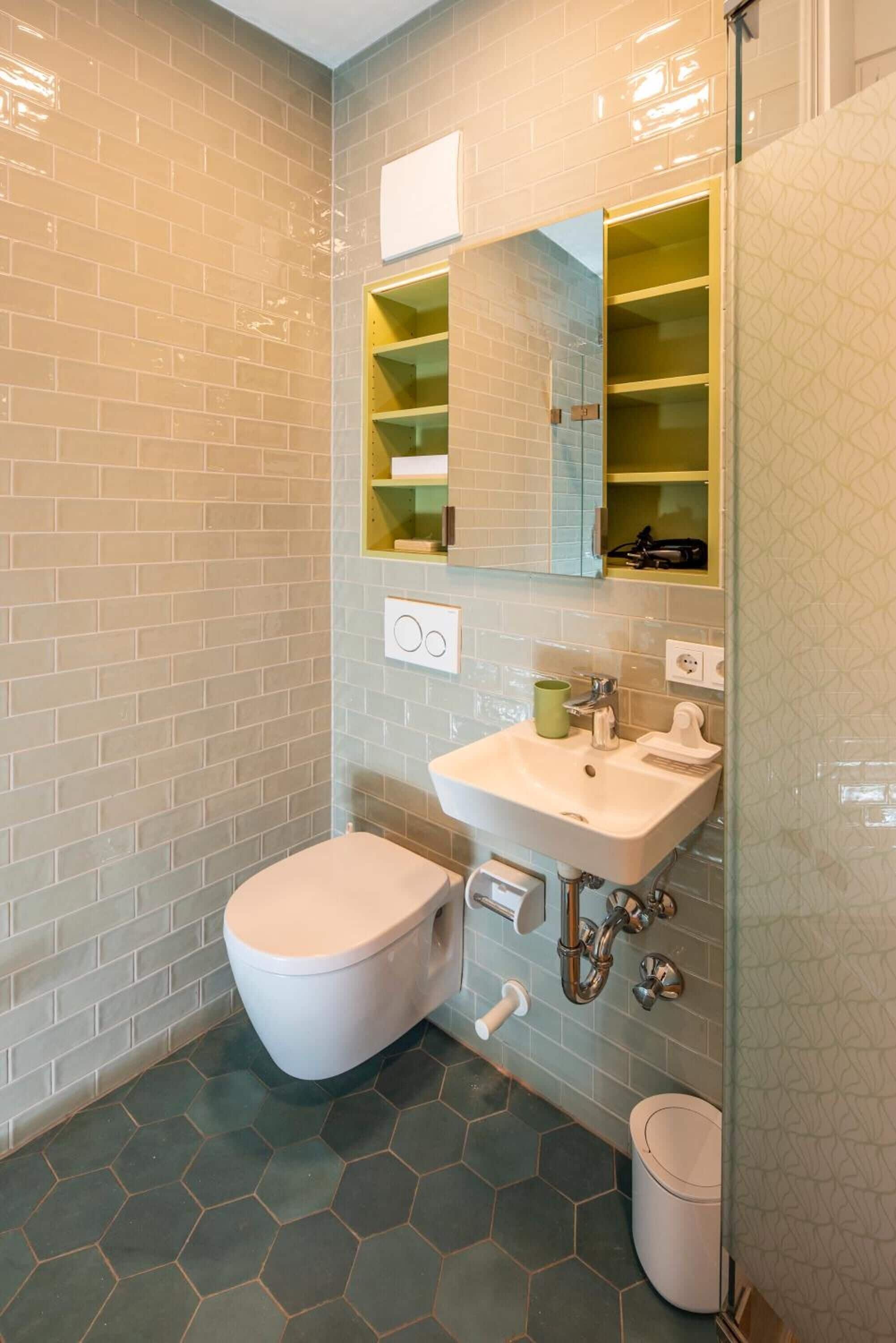 Un baño con inodoro blanco, lavamanos con espejo y cabina de ducha de vidrio.