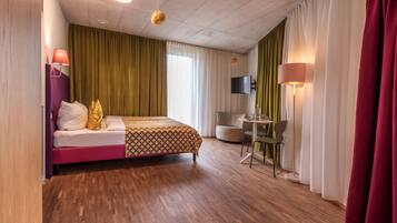 A hotel room with a bed, a desk, a chair, and a TV.
