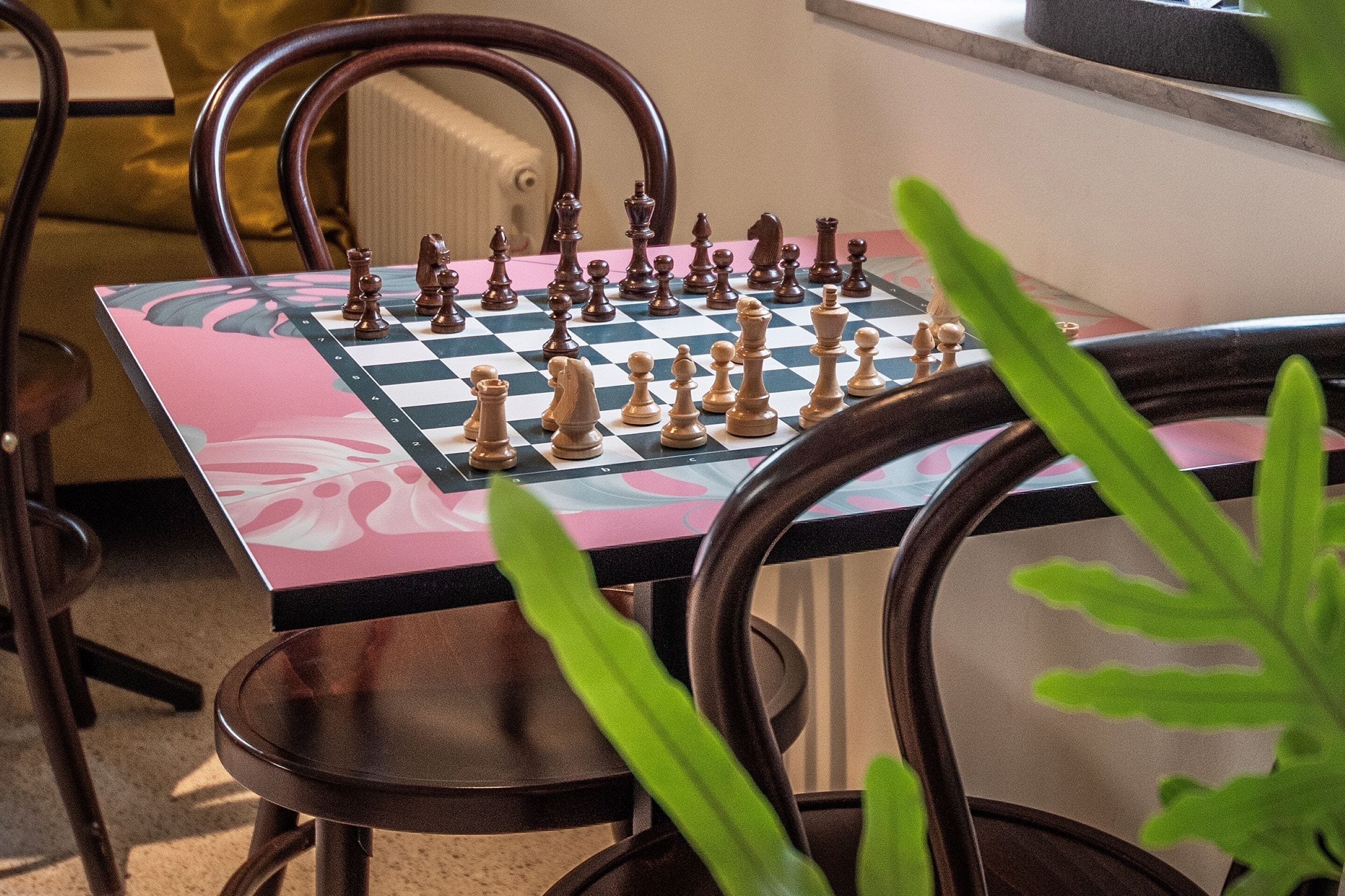 Un tablero de ajedrez sobre una mesa, con sillas a su alrededor.