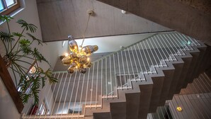 A modern staircase with a glass railing, a unique light fixture, and a potted plant. - pradl elf my - apartment (Innsbruck)