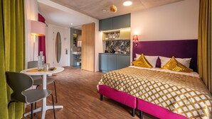 A modern hotel room with a bed, a dining area, and a kitchenette. - pradl elf my - apartment (Innsbruck)