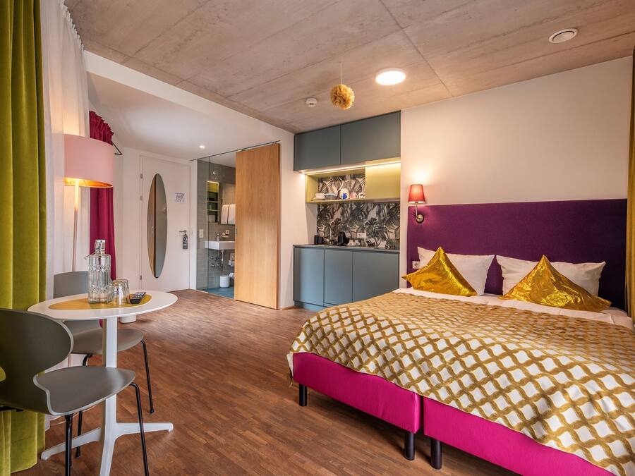 Une chambre d’hôtel moderne équipée d’un lit, d’un coin repas et d’une kitchenette.