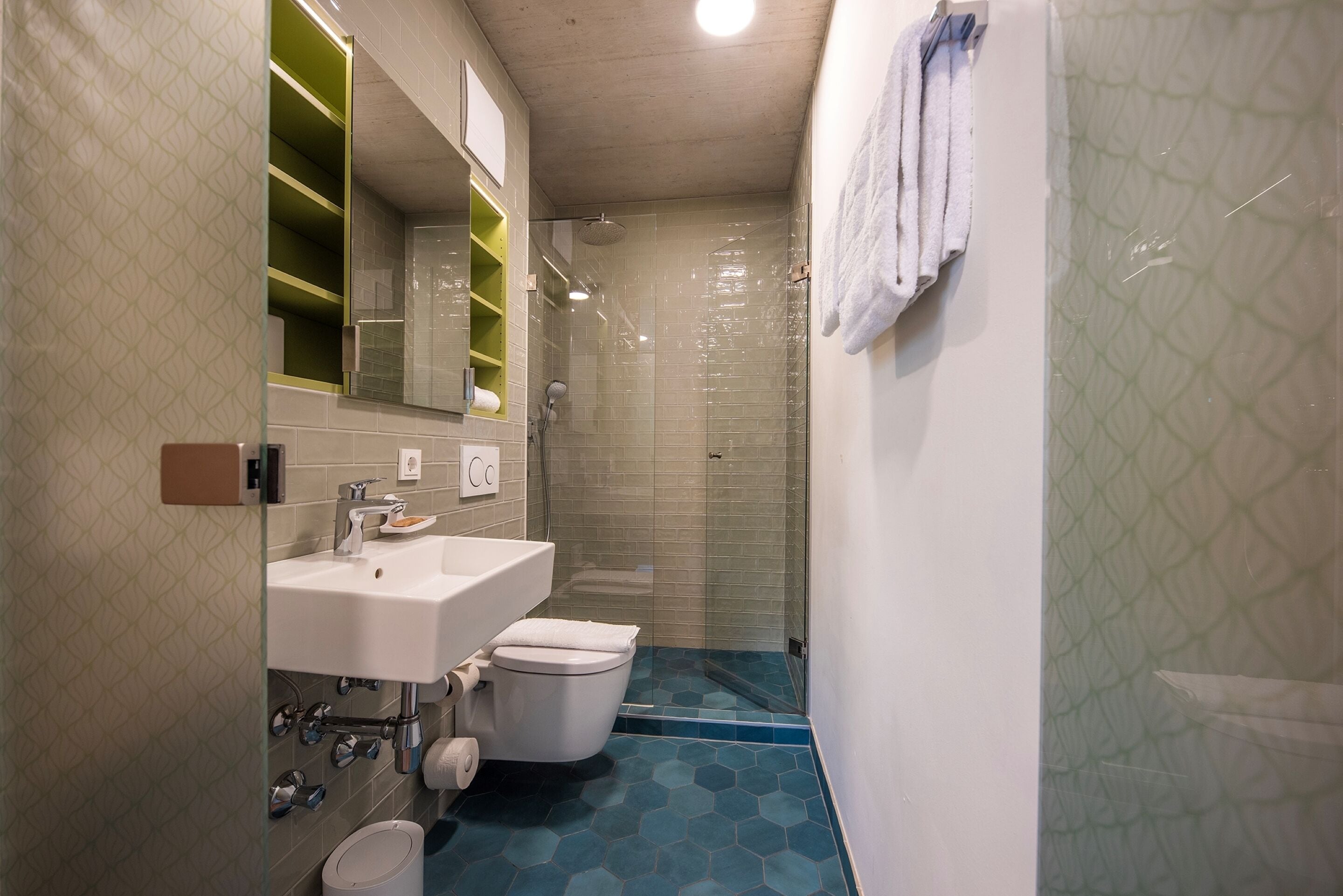 A bathroom with a glass-enclosed shower, a white sink, and a toilet.