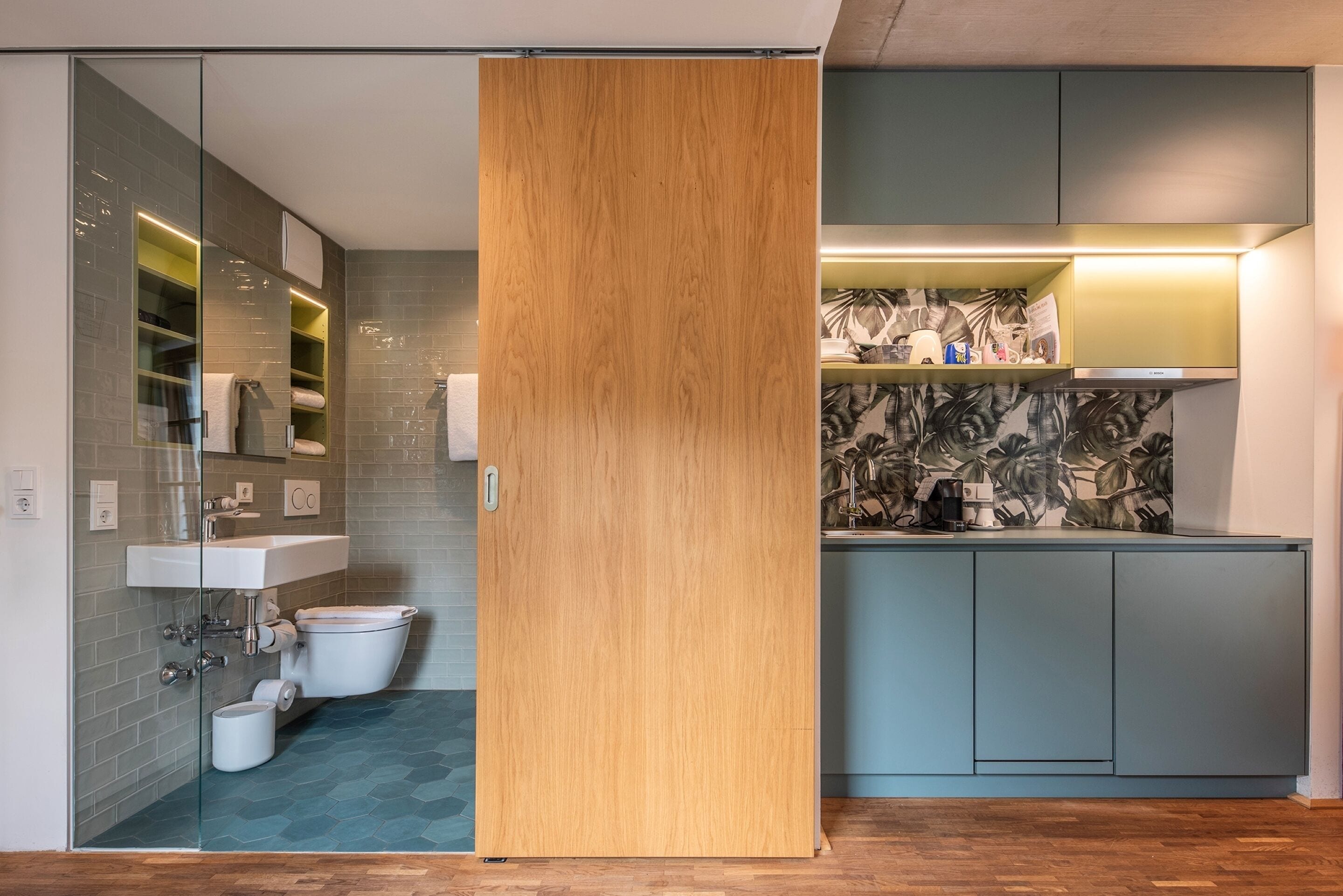 Une salle de bain moderne avec une douche à parois de verre, une porte coulissante en bois, des toilettes et un lavabo.
