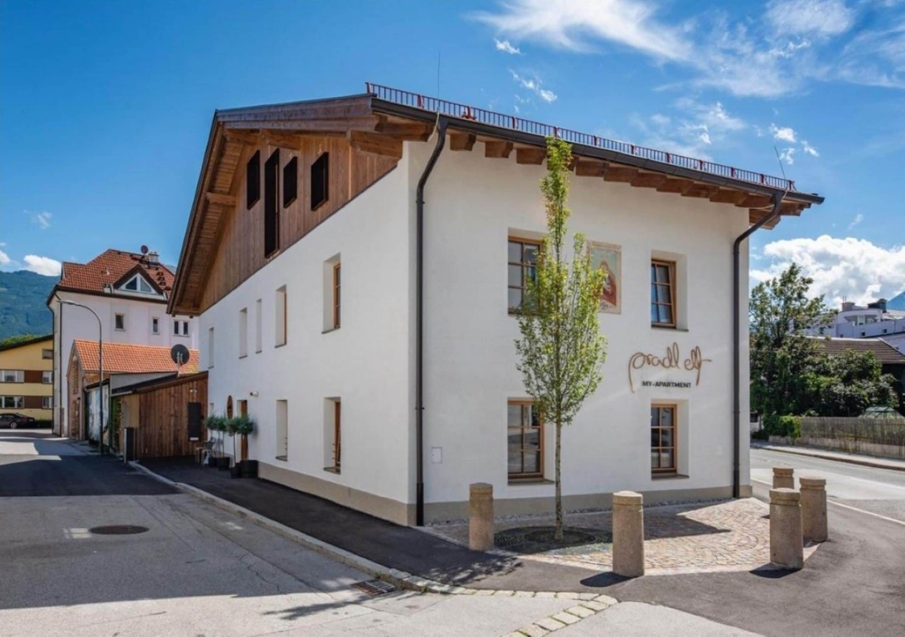 A two-story building with a white facade, wooden beams, and a balcony.