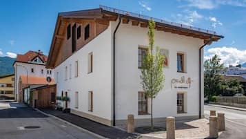 Un edificio de dos pisos con fachada blanca, vigas de madera y un balcón.