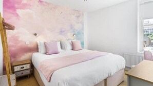 A bedroom with a bed, bedside table, and a window with a view. - Stylish Flat with Stunning Sea Views, Ilfracombe (Ilfracombe)