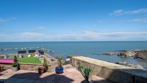 A terrace with a view of the sea, potted plants, and a flag. - Stylish Flat with Stunning Sea Views, Ilfracombe (Ilfracombe)