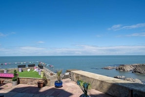 Una terraza con vista al mar, plantas en macetas y una bandera.