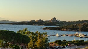A marina with boats docked, surrounded by greenery and hills. - Blue Bay Apartment Baja Sardinia (Arzachena)