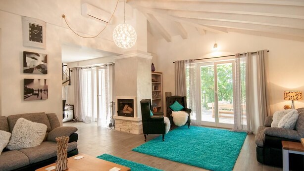 Un salon spacieux avec une cheminée, des tapis turquoise et un lustre moderne.