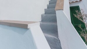 A white building with a staircase leading to a green door. - Terramare Guesthouse (Procida)