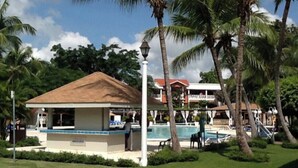 A resort with a pool, palm trees, and a building with a red roof. - Room-private Room in the Boca Chica Reso (Boca Chica)