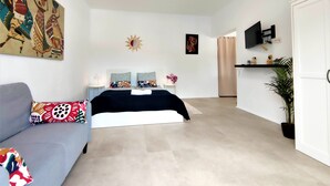 Une chambre à coucher moderne avec un lit, un canapé, une télévision et des œuvres d’art accrochées aux murs.