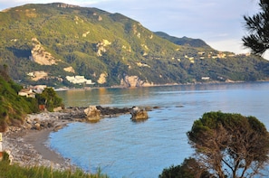 A coastal landscape with a rocky shoreline, a clear blue sea, and a mountainous backdrop. - Villa Philippos on Dechoumenes Beach - Agios Gordios, Corfu (Corfu)