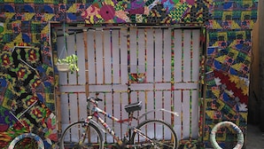 A bicycle parked in front of a colorful, patterned wall with a decorative gate. - Room-the Village Apartments, Gbagada (Lagos)