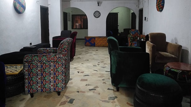 A room with patterned sofas, a dartboard, and a chessboard. - Room-the Village Apartments, Gbagada (Lagos)